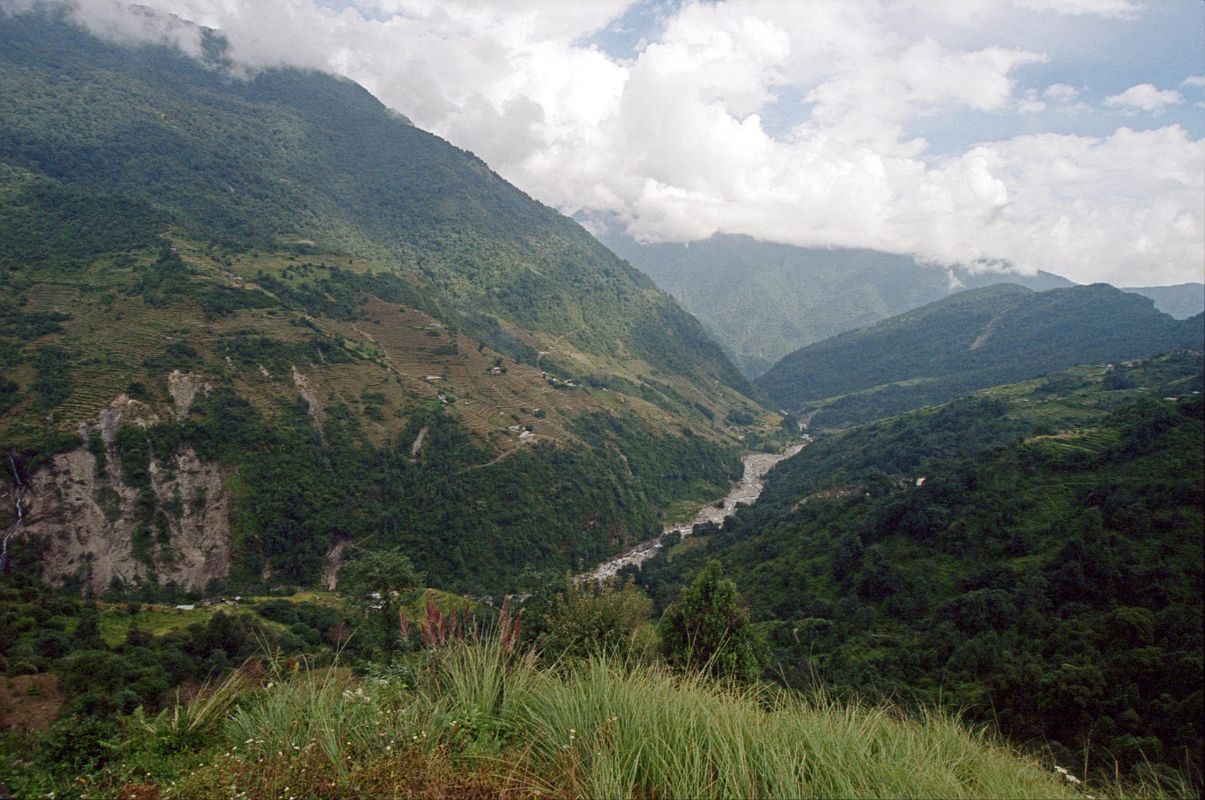 605 Looking Towards Chomrong From Chiule With Khumnu Khola Below I descended from Tadapani once again with a forest canopy to Chiule (2170m). I was pleased to finally leave the forest behind as I emerged into the open. The descent was steep again all the way to the bridge over the Khumnu Khola at 1930m, arriving at 13:00. The trail went steeply up the other side before leveling off as I passed thru Ghurjung (2010m). Once again I had to huff and puff steeply up before the trail finally leveled off all the way to Chomrong (2210m), arriving at 15:00